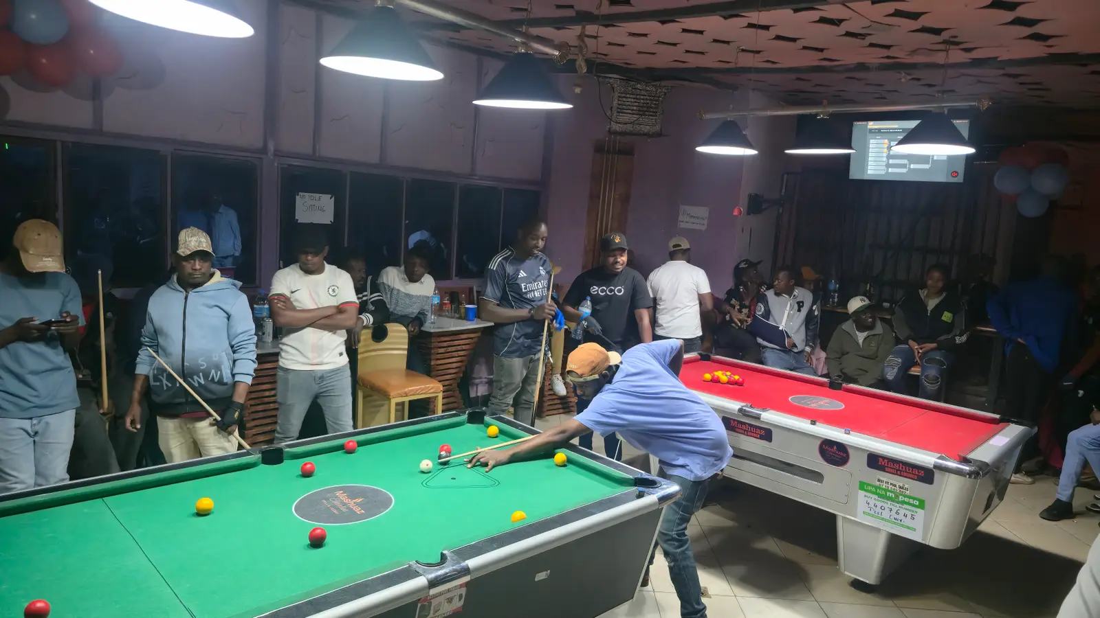 A bright, well-run pool room with the bracket on the TV at Mashuaz, Loitokitok